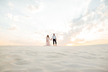 young couple a guy in black breeches and a girl in a pink dress are walking along the white sand - Powered by Adobe