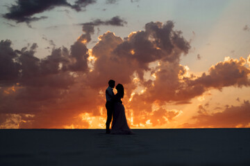 young couple a guy in black breeches and a girl in a pink dress are walking along the white sand