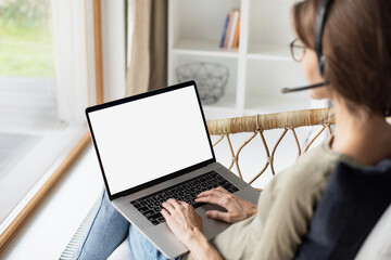 Young woman working at home, Student girl wearing headset using laptop computer with empty white blank screen, meeting online, web conference, studying, e-learning, technology concept