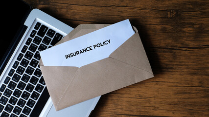 Insurance Policy Card In Envelope on laptop background.	