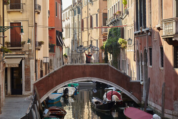 Man raises his mountain bike to the sky. He stands on a bridge in Venice/Italy. Bicycle tours invigorate the mind and make creative. The best against depression. 