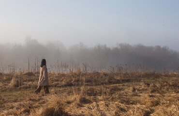 girl in  beige raincoat walking on  sunny day