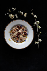 WHITE VINTAGE DISH ORGANIC PORRIDGE HEALTHY TOPPINGS SPRING CHERRY BLOSSOM ON BLACK BACKGROUND 