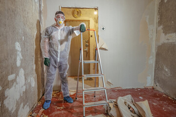 Apartment renovation. The builder in a protective suit, respirator and goggles.