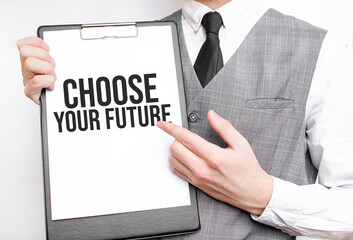 CHOOSE YOUR FUTURE inscription on a notebook in the hands of a businessman on a gray background, a man points with a finger to the text
