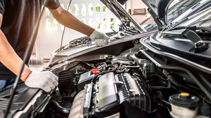 Close-up hands of auto mechanic are using the wrench to repair and maintenance auto engine is problems at car repair shop. Concepts of car care check and fixed and services insurance.