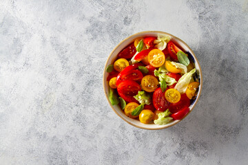 Salad of red and yellow tomatoes with herbs, in a cup, top view, free space