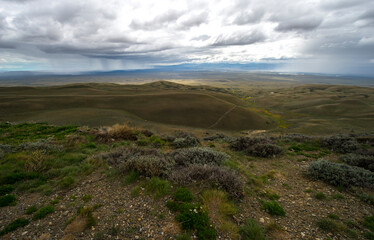 view of Patagonia hills with shadows and storm clouds with wall of shower going on the soil 