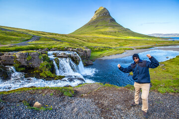 A young man at Kirkjufellsfoss on a summer morning at the waterfalls. Iceland