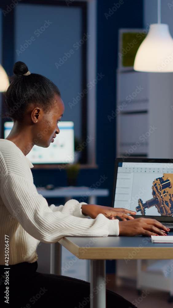 Aufkleber african engineer working late at night on a 3d model of industrial gears at laptop doing overtime in
