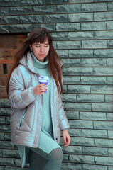 Young has driven up the steps with a silicone ecological reusable cup in his hands against a grey brick wall. High-quality photo