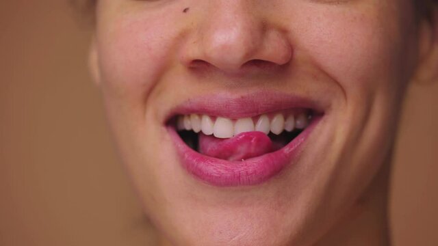 Close up macro portrait of African American woman licking her lips with tongue and biting her lower lip with teeth. Face of black female with natural beauty. Slow motion ready, 4K at 59.94fps.