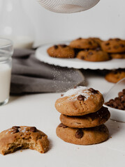  Chocolate chip Cookies on white table concept shot with milk, green cactus grey napkin