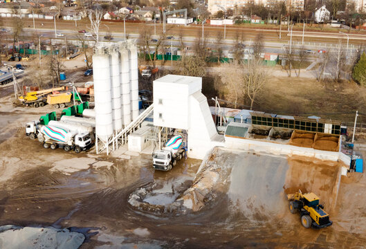 Ready mix concrete batching plant. Producing сoncrete and portland cement mortar for construction and formworks. Pouring concrete through to a ready-mixed truck. Drone view. Out of focus