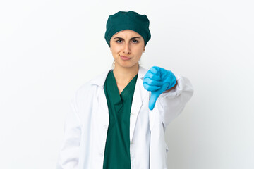 Surgeon caucasian woman isolated on white background showing thumb down with negative expression