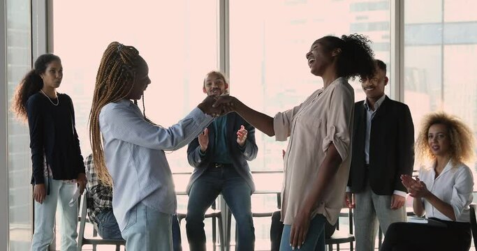 African ethnicity businesswoman leader congratulates office employee with promotion career advance shake hands express respect, diverse company staff clap hands cheering showing amity. Praise concept