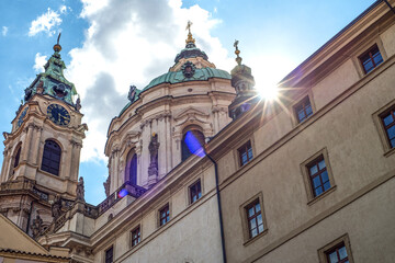 Obraz premium An old church, a church in Prague, Czech Republic. Clear sunny sky. The bright sun that shines into the frame. Green domes. Ancient architecture.