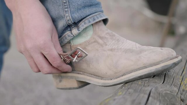 Cowboy put on spurs on boots close-up 4K