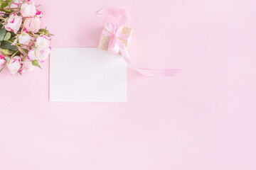 Gift box, flowers and greeting card on pink background. Flat lay. Birthday, wedding, anniversary or mother's day concept.