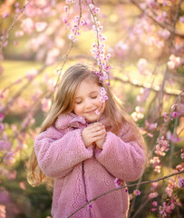 Little smiling girl in blooming sakura park. Spring concept of blooming nature.
