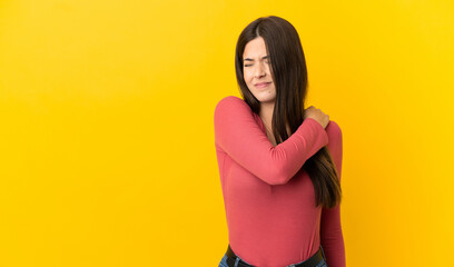 Teenager Brazilian girl over isolated yellow background suffering from pain in shoulder for having made an effort