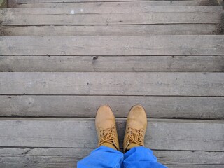 legs build on the steps of a wooden staircase first person view