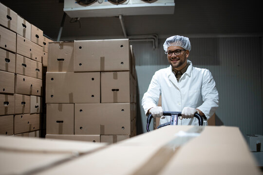 Factory Worker Moving Packages With Fresh Organic Food In Cold Storage.