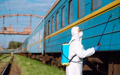 Man in Hazmat suit, protective gloves and goggles use sprayer equipment disinfect a train. Covid-2019.