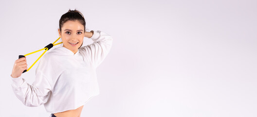 Banner, long format. Young athletic girl with drag rope elastic band on white studio background with side space for text or advertising.
