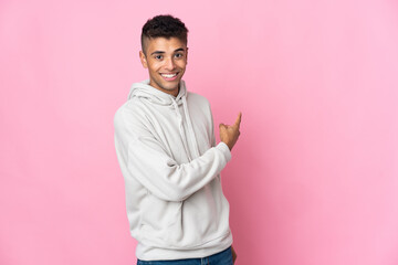 Young Brazilian man isolated on pink background pointing back