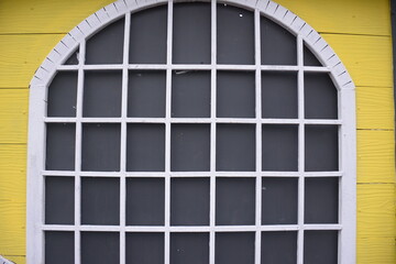 classic wooden house windows with a yellow and white color combination.