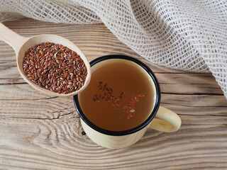 Herbal drink tea and linseed in wooden spoon, napkin on wooden background, top view, flat layout. A useful linum plant with omega and vitamins for use in medicine and vegetarian dietary nutrition
