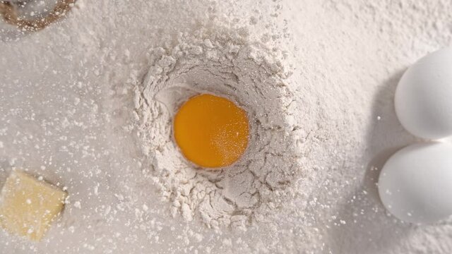 Raw Egg Yolk Falling into Pile of Flour Making Hole in Slow Motion 1000fps - Top View