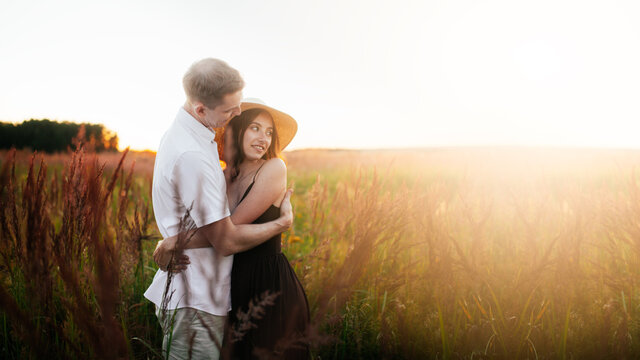 Stylish charming Caucasian young couple hugging in summer at sunset, romantic photo at sunset. Man and woman together 