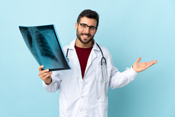 Professional traumatologist holding radiography isolated on blue background holding copyspace imaginary on the palm
