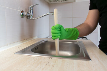 Drain Problems, blockage plumbing kitchen sink unclog plunger man hand hold