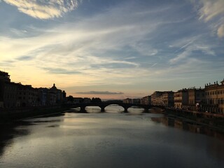 Fototapeta na wymiar Sunset from the golden bridge in Florence. Ponte Vecchio. Reflection. Italy. Boat, sunset, light, twilight, sky. Arno river, bridge