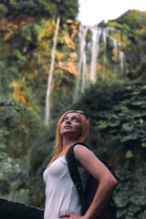 Tourist girl pose, look at waterfall in Italy (Cascata delle Marmore) in Umbria. small, calm water pressure. Evening, sunset. Summer, vertical photo. Front view