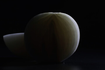 Fresh onion bulbs on black background. Bulb onion is rich in vitamins, useful spring. Onion peel on a dark background. Raw sliced onions.