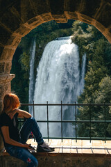 Tourist girl look at waterfall in Italy (Cascata delle Marmore) in Umbria. Large water pressure,...