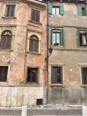Fragment of Verona street. Italy. Plant in pot. Colorful. Window and shabby wall. Cobblestone. Date of photo is 02.05.2018
