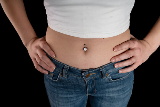 Belly button or navel piercing of sexy young woman isolated on black background. Horizontal shot.