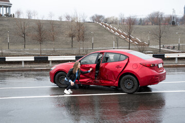 Obraz na płótnie Canvas Woman sits near a broken car after an accident. call for help. car insurance