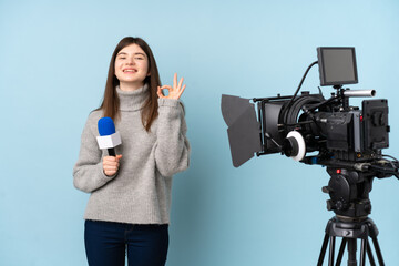 Young reporter woman holding a microphone and reporting news showing an ok sign with fingers