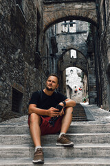 A man sitting on the steps. Use smartphone. Narni (Terni, Umbria, Italy), medieval city: a typical...