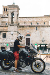 Handsome man in white helmet sitting on old adventure motorbike. Travel and vacation concept....