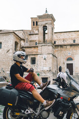 Fototapeta na wymiar Handsome man in white helmet sitting on old adventure motorbike. Travel and vacation concept. Freedom. Vertical photo. Narni, Italy