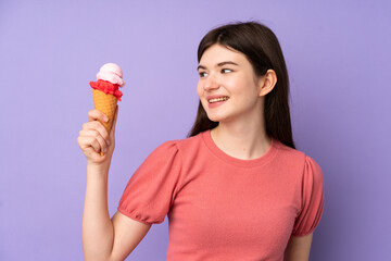 Young Ukrainian teenager girl holding a cornet ice cream over isolated purple background with happy expression