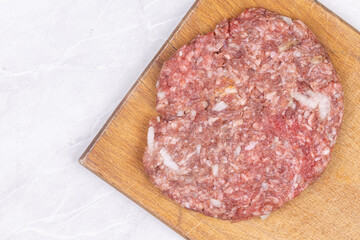 Top view of raw minced meat pljeskavica on the wooden board with copy space