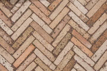 The texture of paving stones. Herringbone pattern on the road in the park. Zigzag paving stone covered with gravel.